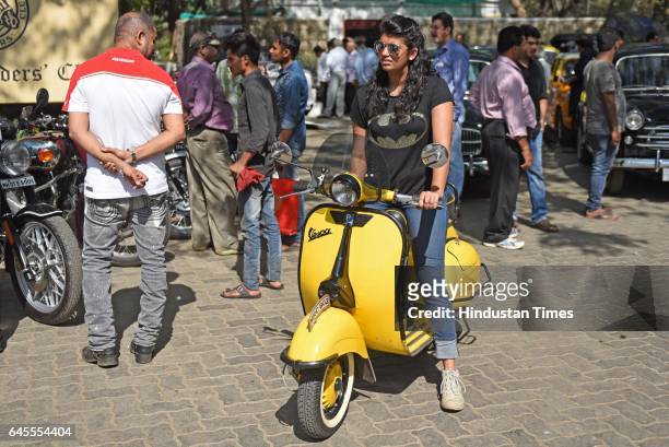 Girl rides on a yellow colour Vespa during the display and inspection of Vintage Cars at Mahalaxmi Race Course, on February 25, 2017 in Mumbai, India.