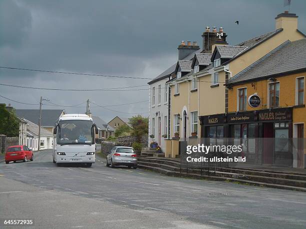 Durch die Hauptstraße der Gemeinde fährt ein Touristenbus, aufgenommen am 18. Juli 2015 in Kilfenora im Burren-Gebiet