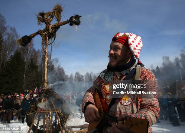 Man plays balalaika as Maslenitsa straw effigy burns during the celebration of Maslenitsa, also know as Shrovetide, or Butter Week, held to mark the...