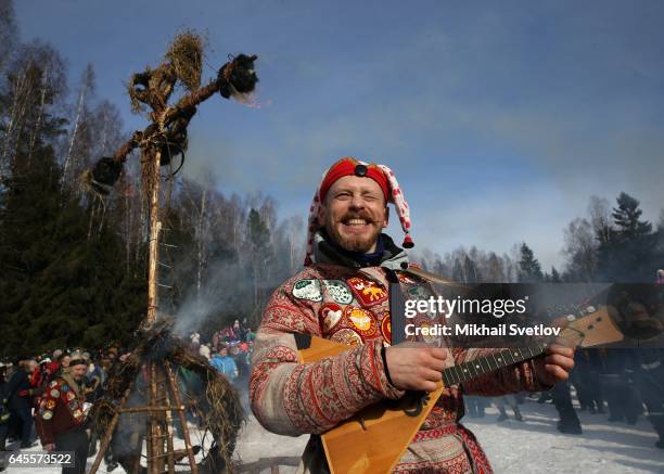 Man plays balalaika as Maslenitsa straw effigy burns during the celebration of Maslenitsa, also know as Shrovetide, or Butter Week, held to mark the...