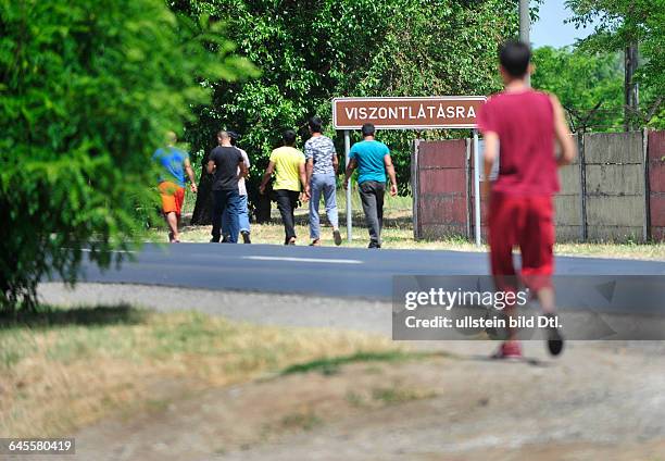 Asian refugee family near Refugee Camp in Debrecen, Hungary. In the background "Goodbye" on the board of the city. Today the Hungarian Government...