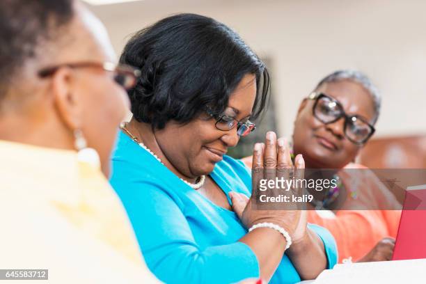 mature black women with friends praying in bible study - black women praying stock pictures, royalty-free photos & images