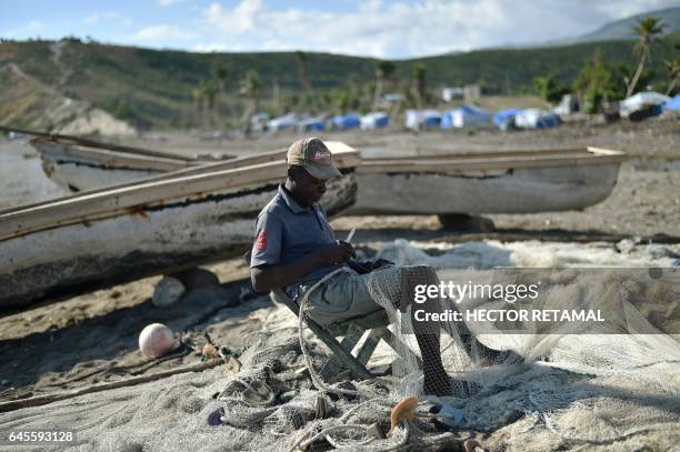 Fisherman repairs nets on a beach damaged by Hurricane Matthew, in the village of Labeyi in the commune of Chardonnieres, southwest Haiti, on...