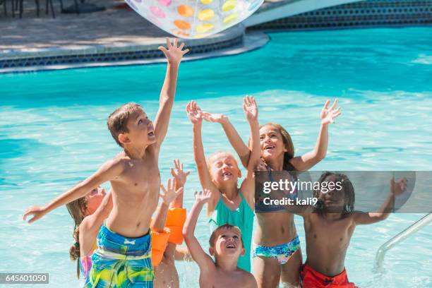 group of children in swimming pool reaching for ball - kids pool games stock pictures, royalty-free photos & images