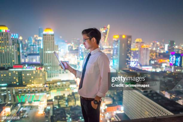 young business man using laptop and digital tablet cityscape background - bangkok business stock pictures, royalty-free photos & images