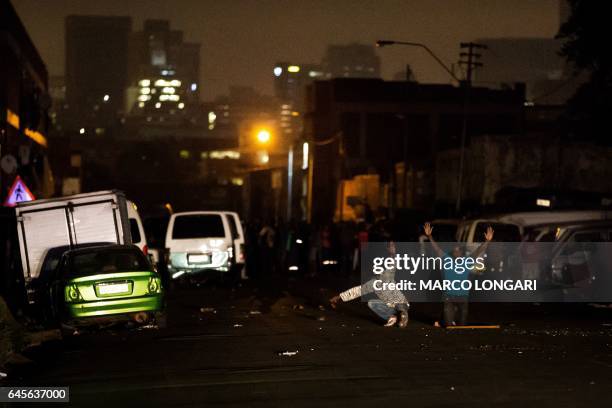 Residents of the worker's hostel in Jeppe's Town neighbourhood of Johannesburg kneel in front of police forces on February 26, 2017. Violence flared...