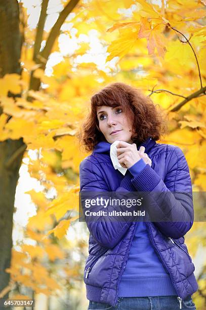 Frau mit Taschentuch in herbstlicher Umgebung, Erkältung