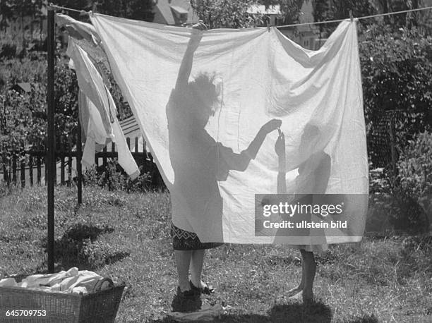 Mutter und Tochter hängen Wäsche auf die Leine, 50er Jahre