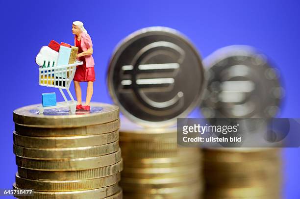 Frau mit Einkaufswagen auf Geldmünzen, gestiegene Verbraucherpreise