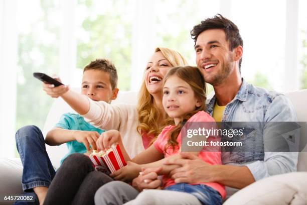 family watching tv on living room sofa - home theatre stock pictures, royalty-free photos & images