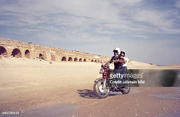 Israel - Ruinen eines Aquaeduktes im antiken Caesarea Maritima, Motorradfahrer am Strand