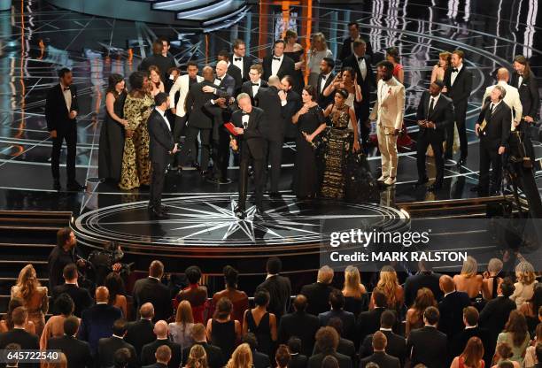 The cast of "Moonlight" and ""La La Land" appear on stage as presenter Warren Beatty , flanked by host Jimmy Kimmel shows the winner's envelope for...