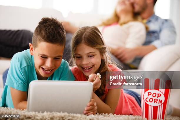 children using digital tablet, eating popcorn - popcorn floor stock pictures, royalty-free photos & images