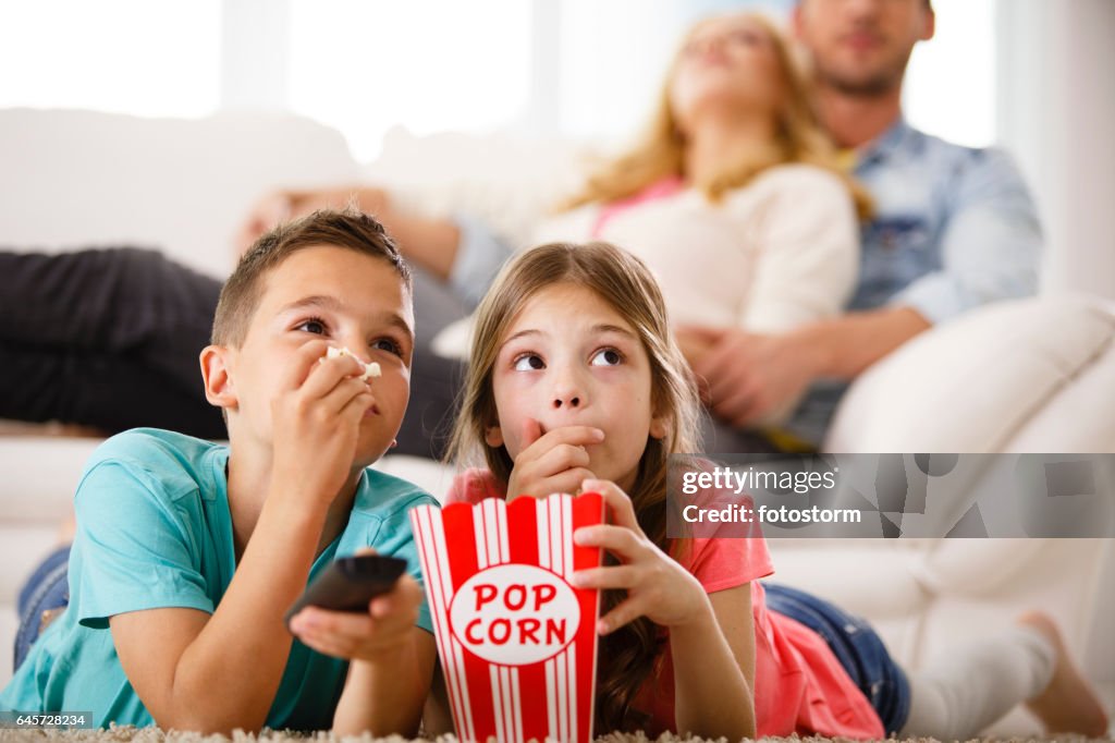Niños viendo televisión, comiendo palomitas de maíz