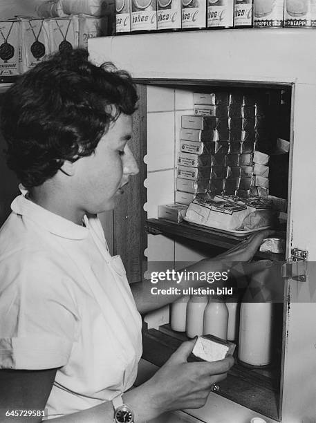 Lebensmittelverkäuferin am geöffneten Kühlschrank, 50er Jahre