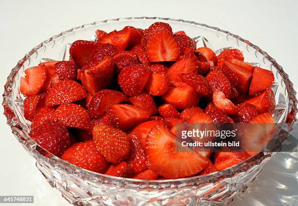Rote reife Erdbeeren als Obstkompott in einer Kristallschuessel auf dem Terrassentisch im Garten