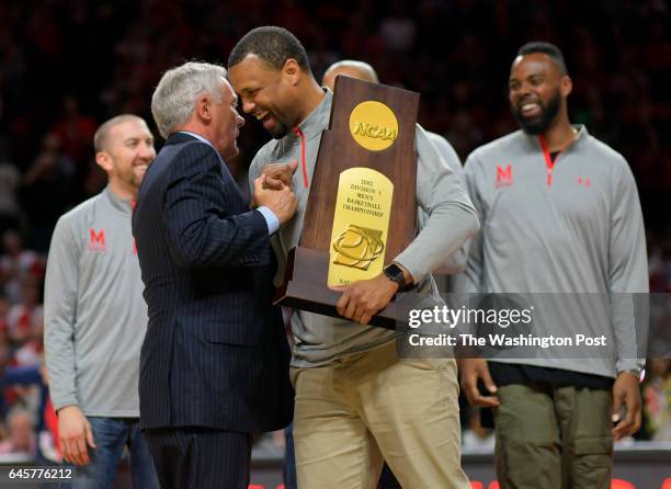 Former Maryland basketball coach Gary Williams greets Byron Mouton who holds the national championship trophy that they won in 2002 during a half...