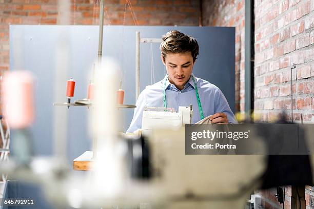 male seamstress working on sewing machine - fashion designer stock pictures, royalty-free photos & images