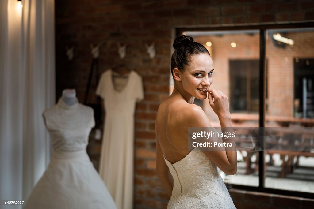 Smiling woman in wedding dress is biting nail