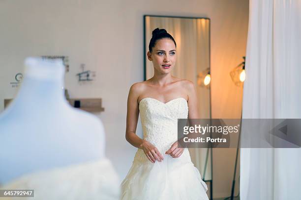 woman wearing wedding gown at bridal shop - robe de mariée photos et images de collection