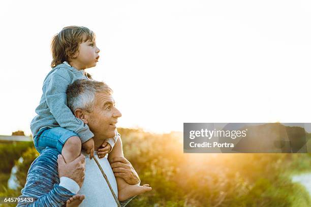 surprised father carrying son on shoulders - person auf den schultern tragen stock-fotos und bilder