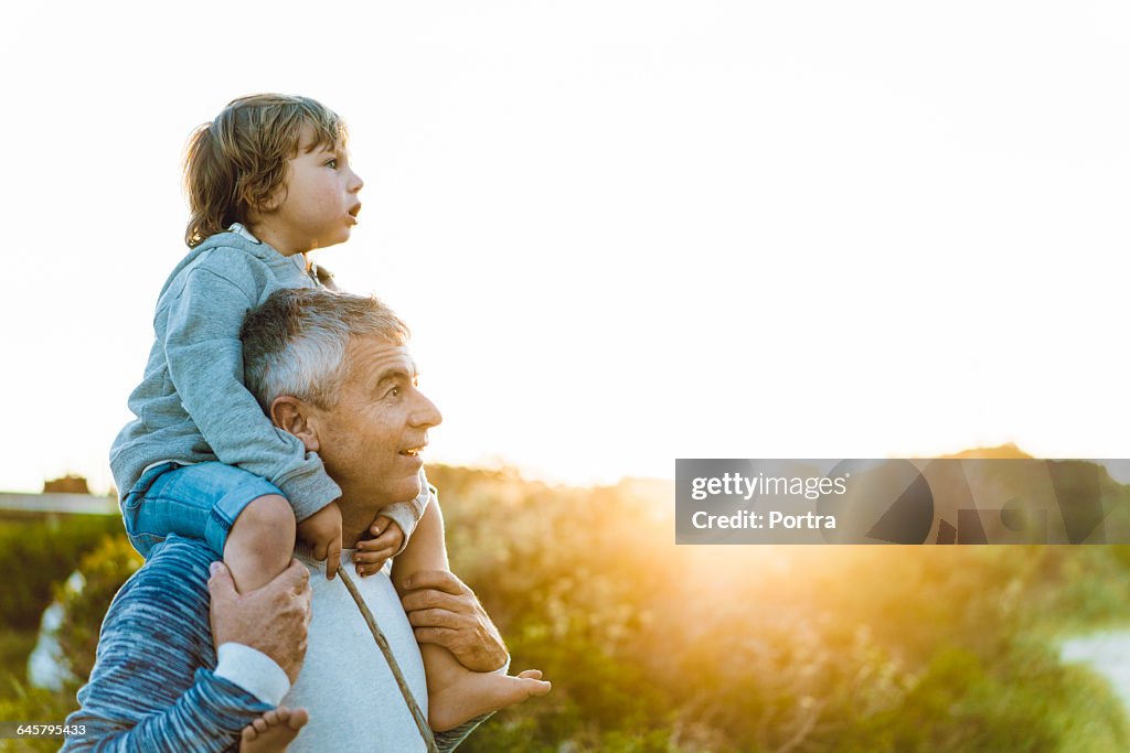 Surprised father carrying son on shoulders