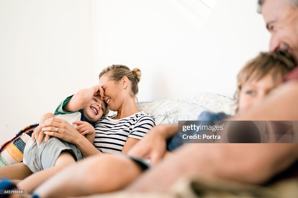 Smiling parents are embracing sons at home