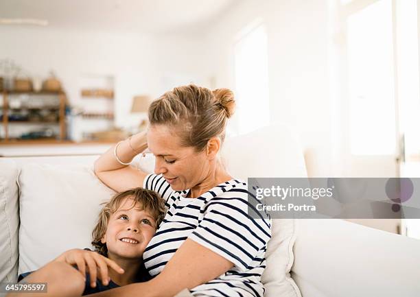 mother talking to son while relaxing on sofa - mum children stock-fotos und bilder