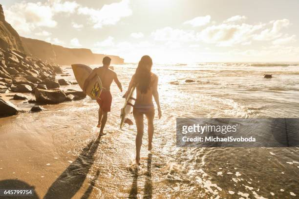 man and women surfers running to the water - san diego people stock pictures, royalty-free photos & images