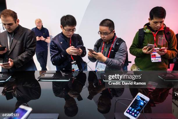 Visitors look at Huawei devices during the Mobile World Congress 2017 on the opening day of the event at the Fira Gran Via Complex on February 27,...