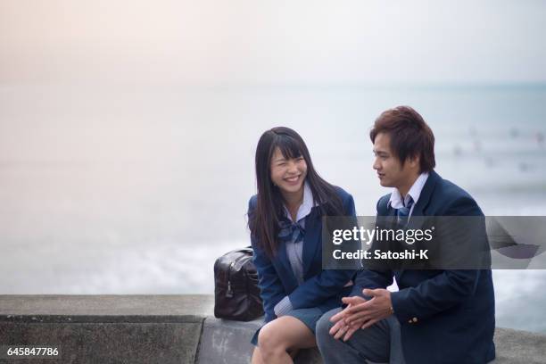 high school student couple being relaxed at beach - japanese school uniform imagens e fotografias de stock