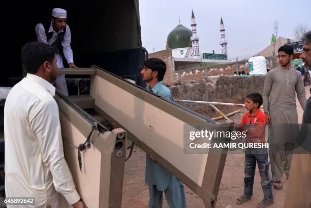 Pakistan followers unload a walk through security gate from a police truck outside the tomb of Mumtaz Qadri, who was hanged last year for the murder...