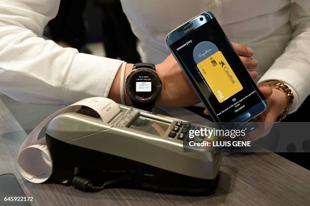 Person shows the "Samsung Pay" system on the first day of the Mobile World Congress in Barcelonaon on February 27, 2017 in Barcelona. - Phone makers...