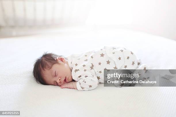 a new born sleeping on a bed - allongé sur le devant photos et images de collection