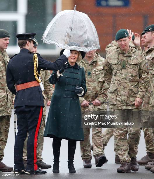 Camilla, Duchess of Cornwall is handed an umbrella by an equerry as she inspects soldiers of 4th Battalion The Rifles during a homecoming parade of...