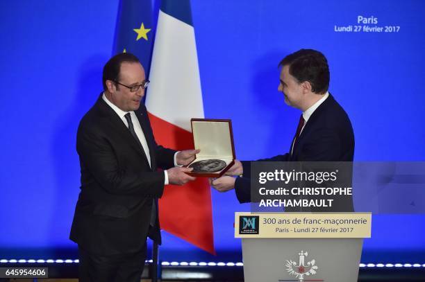 French President Francois Hollande receives a distinction from the Grand Master of the Grand Orient of France Lodge Christophe Habas during a visit...