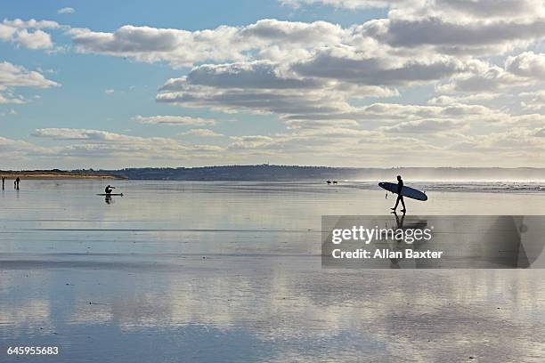 silhouette of surfers across saunton sands - exeter devon stock pictures, royalty-free photos & images