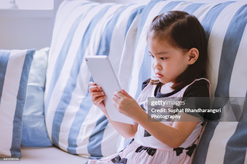 Toddler is reading cartoon on a tablet