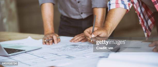 close-up van twee mensen herziening van gebouw blauwdrukken - blueprint stockfoto's en -beelden