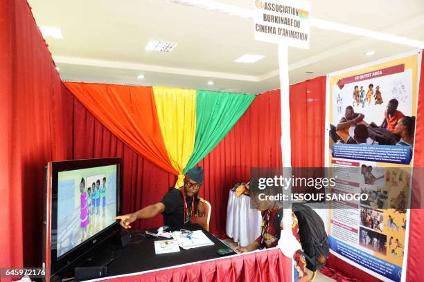 People sit at the stand of the Burkinabe Association of Animated Cinema at the 18th international African television and cinema fair on the sidelines...