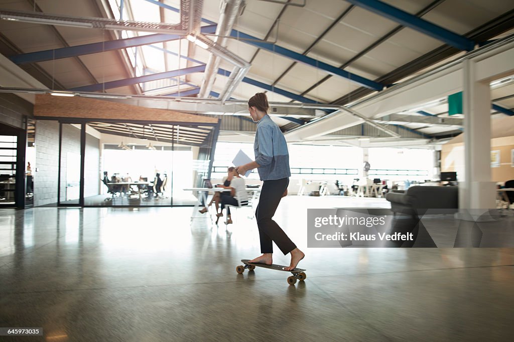 Woman cruising on longboard at creative office