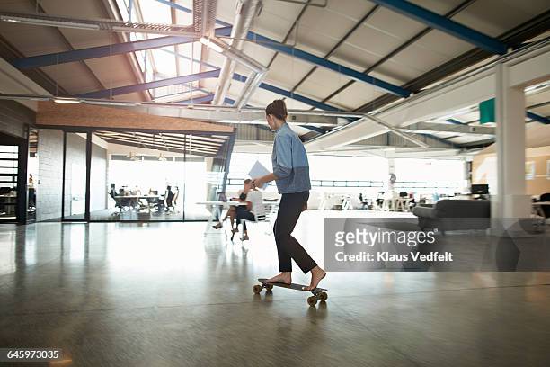 woman cruising on longboard at creative office - cool attitude stock pictures, royalty-free photos & images