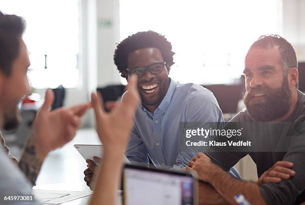 co-workers laughing together at meeting - foco difuso fotografías e imágenes de stock