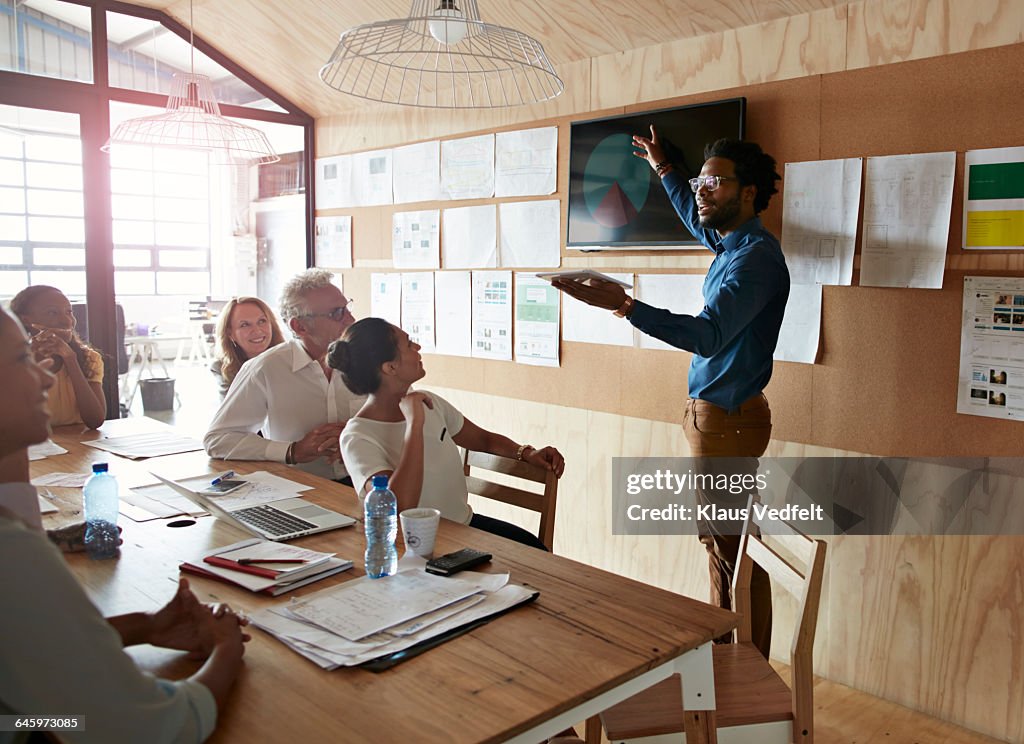 Man doing presentation, using tablet & screen