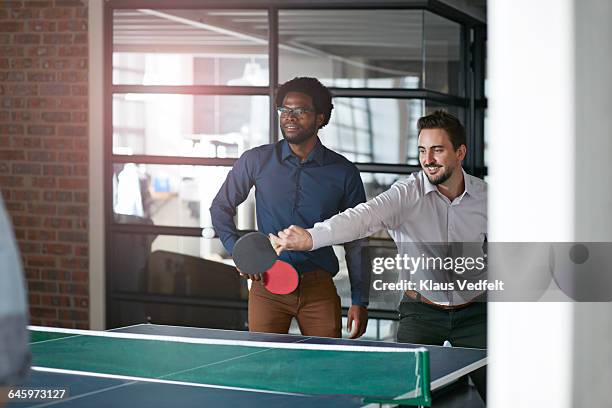 co-workers playing tabletennis at the office - office ping pong stock pictures, royalty-free photos & images