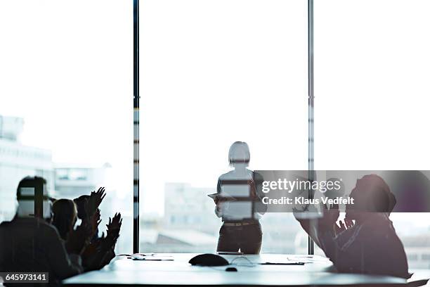 businesswoman presenting, co-workers clapping - multi ethnic business people having discussion at table in board room stock-fotos und bilder