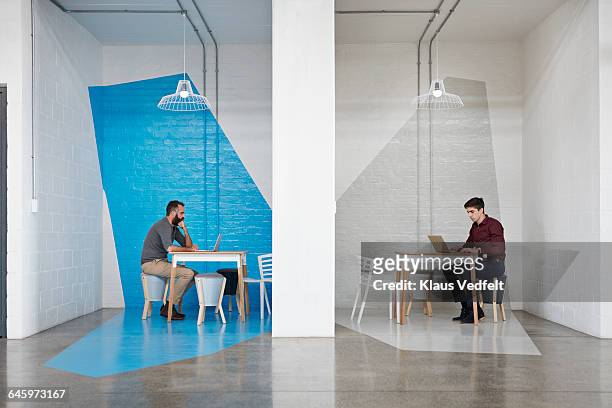 businesspeople sitting in booths,working on laptop - splitsen stockfoto's en -beelden