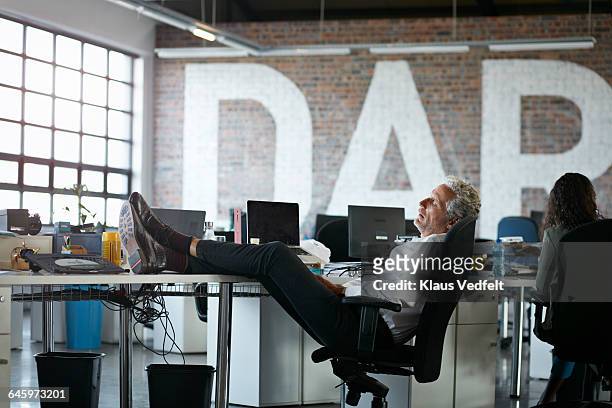 businessman taking a nap, at big open office - nickerchen stock-fotos und bilder