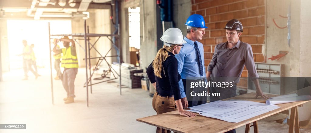 Unternehmer im Gespräch mit Architekten auf Baustelle