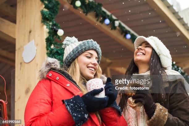 zwei frauen am weihnachtsmarkt - punsch tasse stock-fotos und bilder